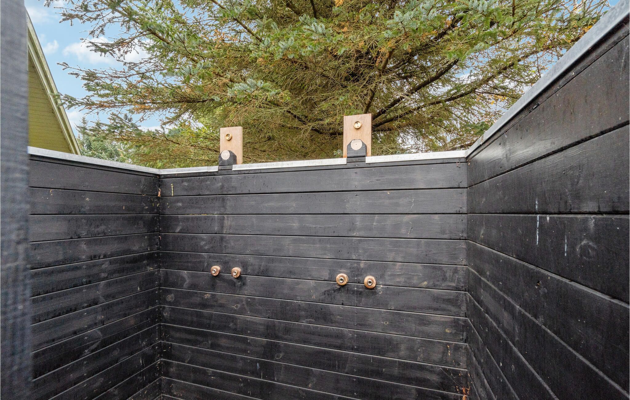Une pièce en bois noir avec deux poutres en bois au plafond et deux poignées en métal sur le mur.