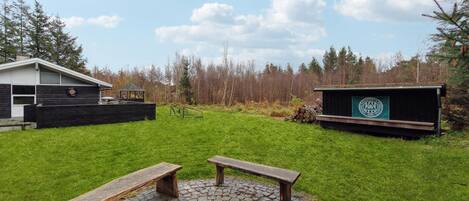 A backyard with a wooden bench, a fire pit, a small shed, and a house with a garage.