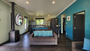 A modern living room with a sofa, a fireplace, a kitchen area, and a dining space.