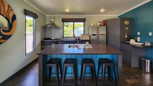 A modern kitchen with a central island, bar stools, a stove, microwave, and a refrigerator.