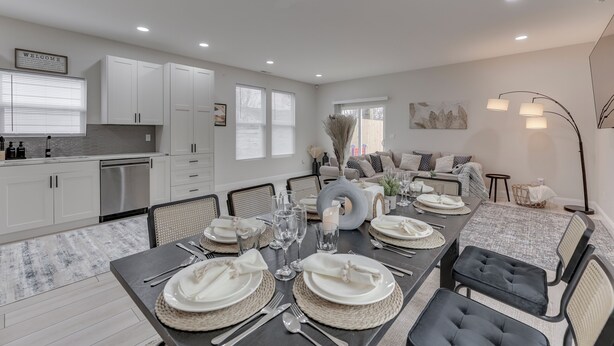 A modern dining area with a large table set for six, surrounded by comfortable seating.