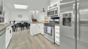 A modern kitchen with stainless steel appliances, white cabinetry, and a dining area with a table and chairs. - Huge CDA Getaway With Foosball And BBQ (Coeur d'Alene)