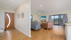 A modern living room with a grey sofa, a pink armchair, and a wooden floor. - 120 Madaffari Drive - Featuring two master suites and a full outside bathroom (Exmouth)
