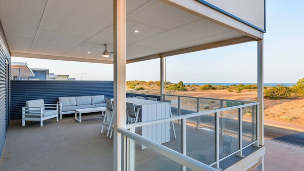 A covered outdoor area with a seating arrangement, a table, and a view of the beach and desert landscape. - 120 Madaffari Drive - Featuring two master suites and a full outside bathroom (Exmouth)