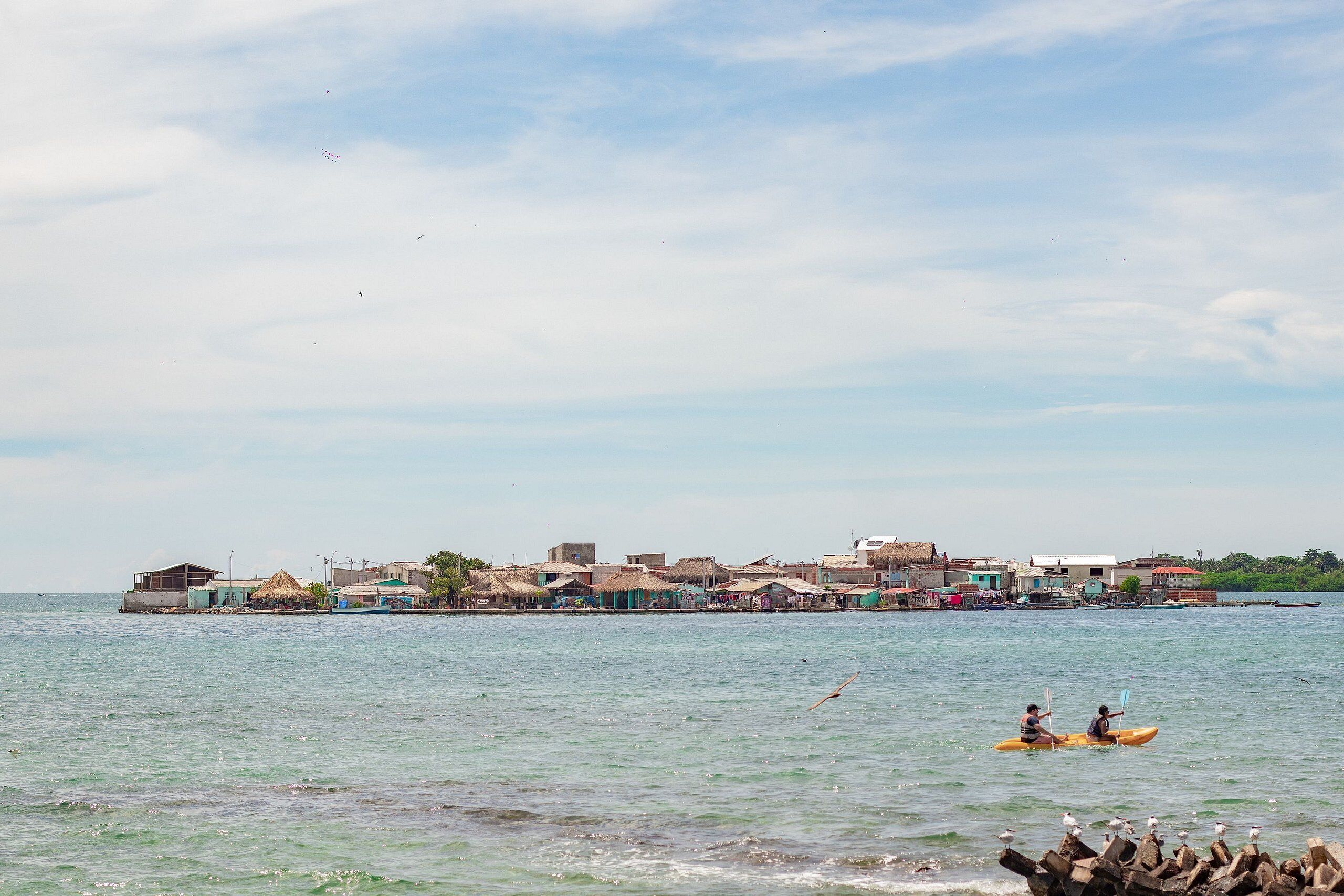Un poble costaner amb cases tradicionals de teules i un mar tranquil.