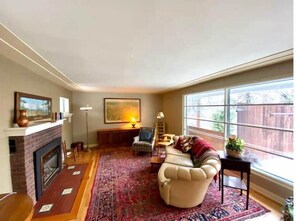 Cozy living room with a fireplace, comfortable seating, and large window.