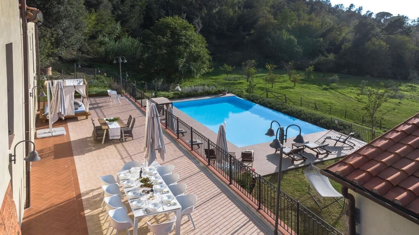 A pool area with a table set for dining, outdoor chairs, and a hammock.