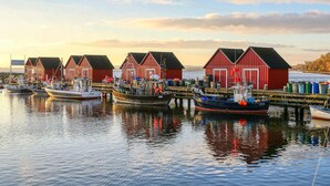 A waterfront scene with red wooden buildings, boats docked, and calm water reflecting the structures. - Beautiful home in Jesendorf with WiFi (Jesendorf)