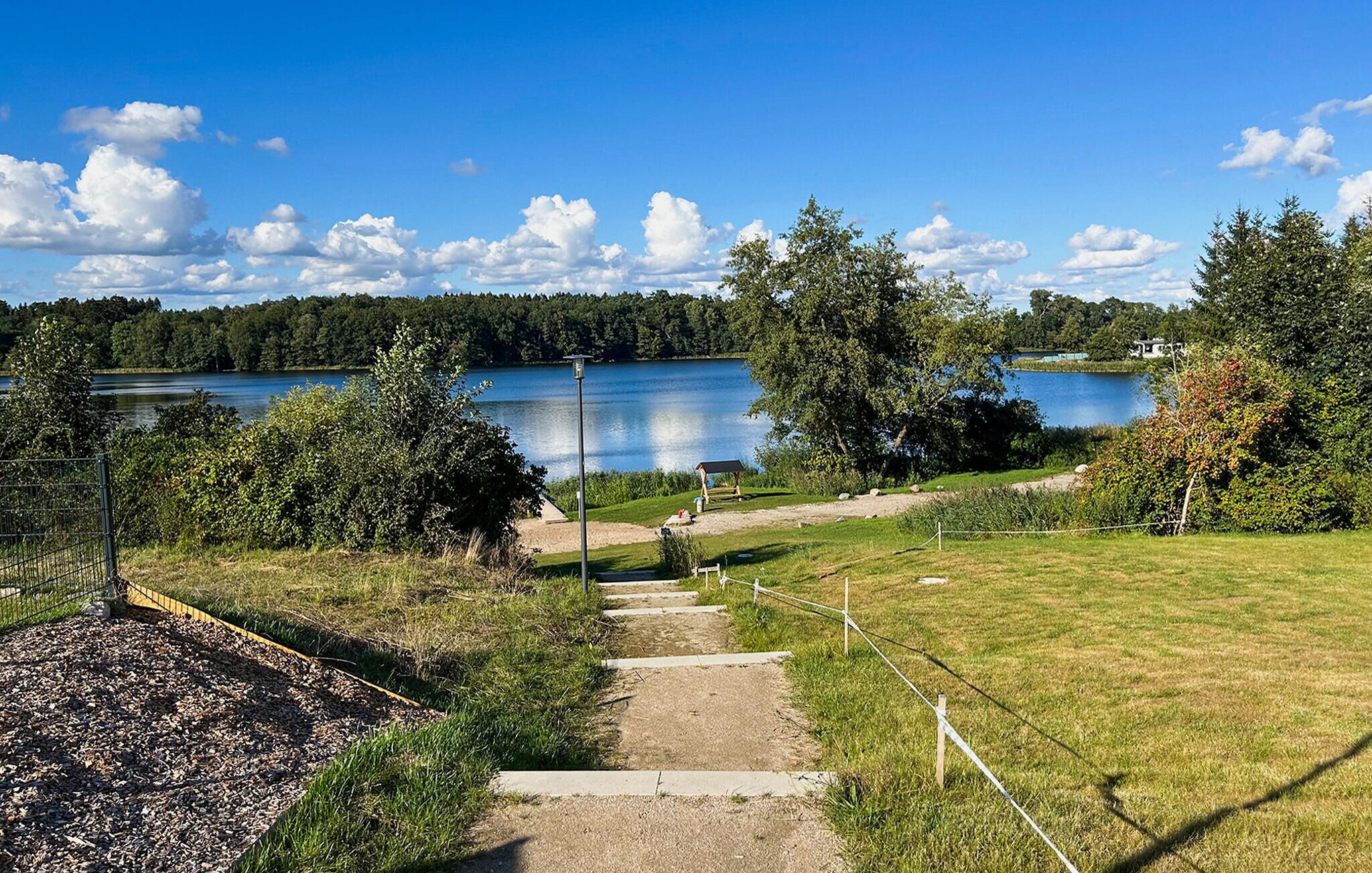 A pathway leading to a lake with a wooden dock and a covered area.