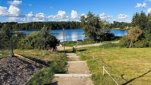 A pathway leading to a lake with a wooden dock and a covered area. - Beautiful home in Jesendorf with WiFi (Jesendorf)