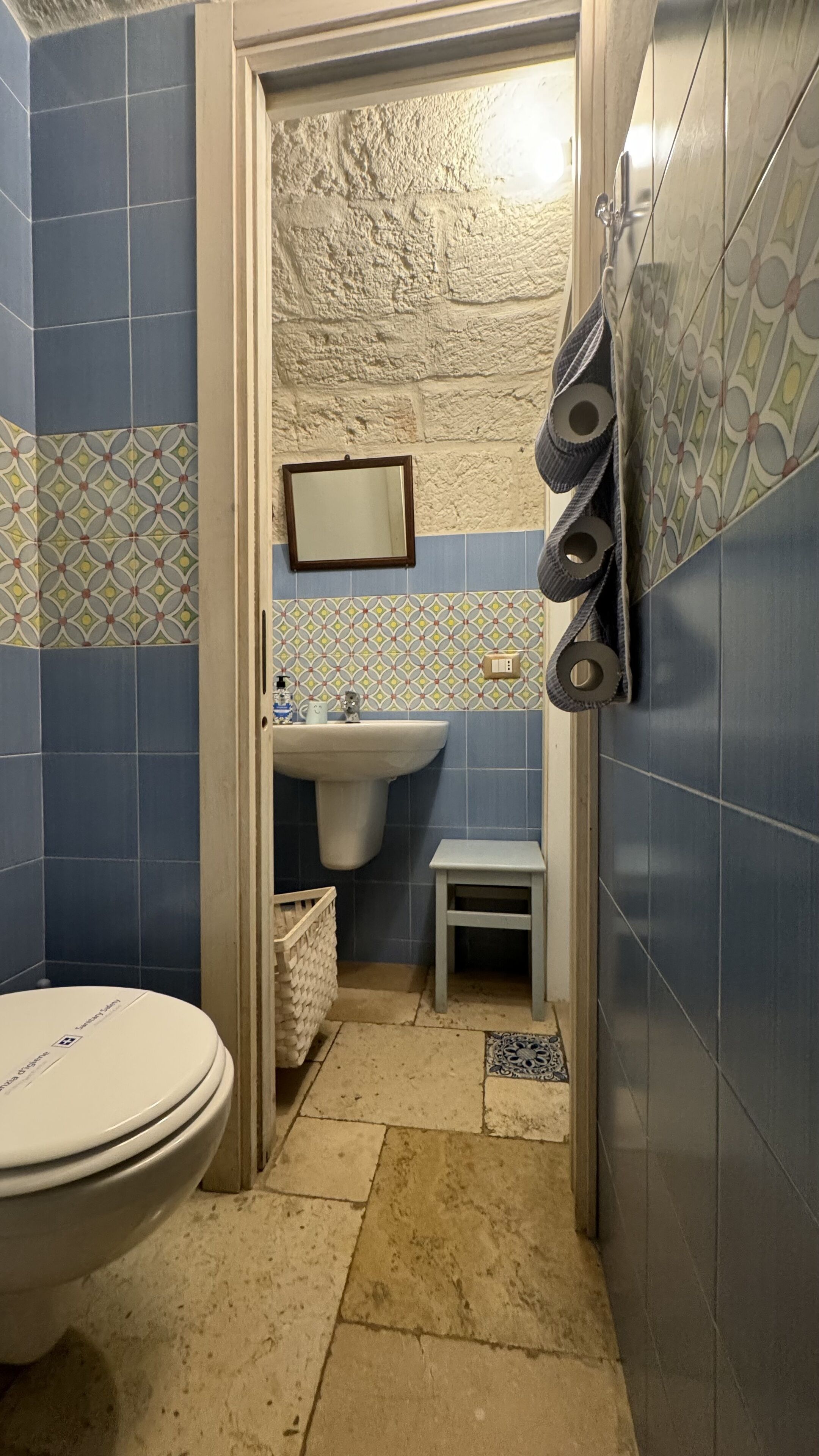 Un baño con inodoro, lavamanos y un pequeño taburete.
