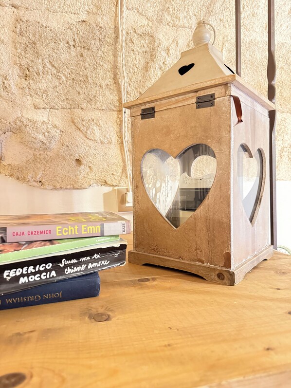 Un farol de madera con una ventana en forma de corazón, colocado sobre una superficie de madera junto a una pila de libros.