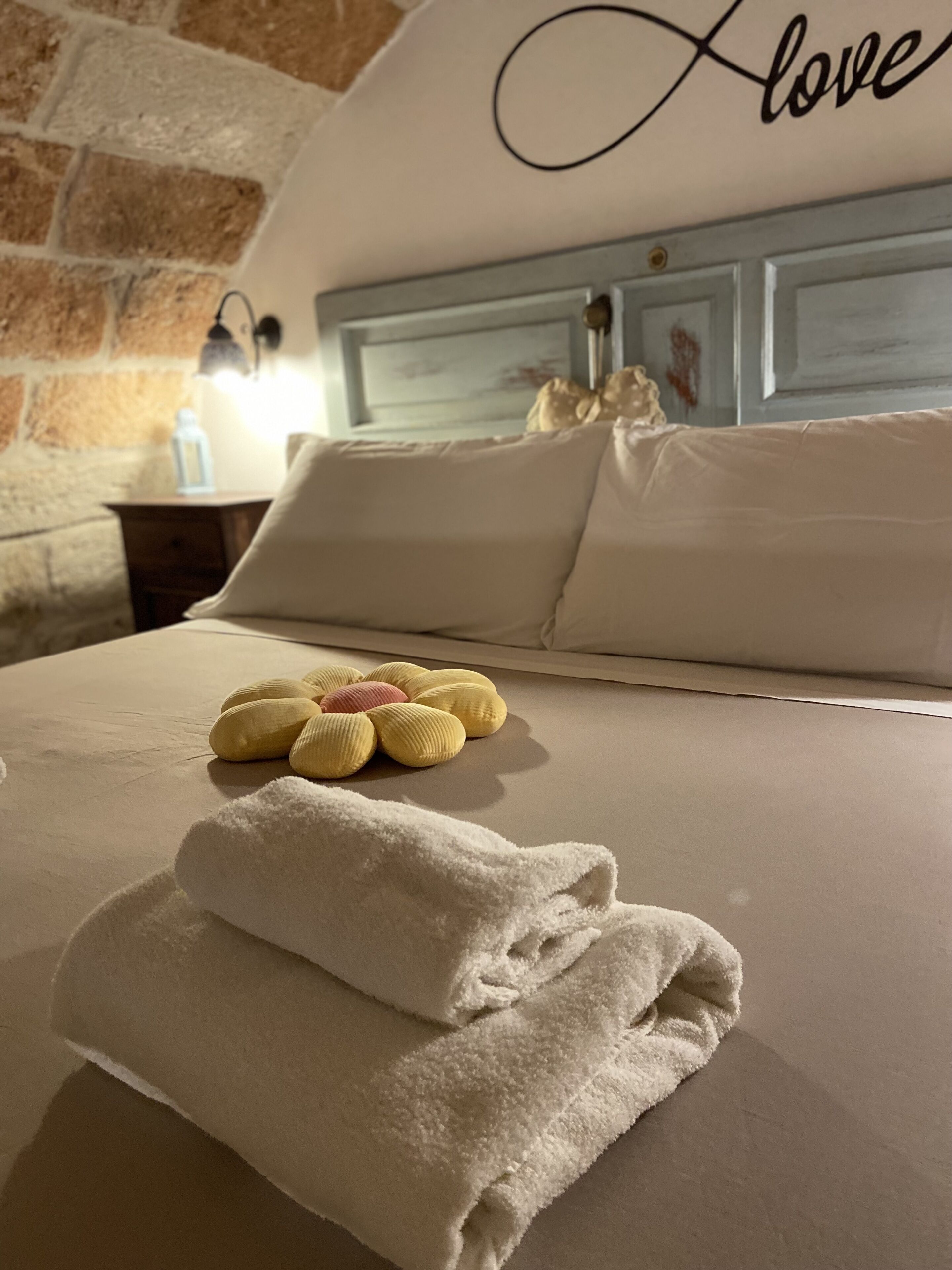 A neatly made bed with a folded towel and a decorative pillow.