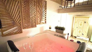A spa area with a large hot tub, stone walls, and a balcony with a railing.