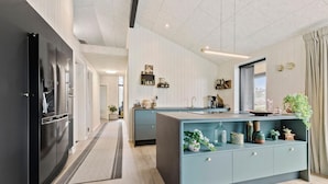 A modern kitchen with a central island, a black refrigerator, and a light blue cabinet. - 4 bedroom gorgeous home in Glesborg (Glesborg)