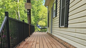 Une terrasse en bois avec des marches menant à une maison dotée d’un porche abrité.