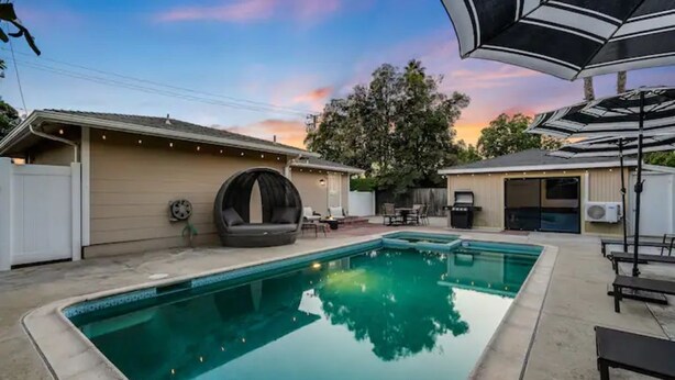 Un patio trasero con piscina, zona de estar techada y terraza amueblada.