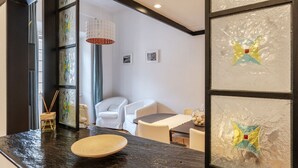 A modern interior with a dark marble countertop, white chairs, a round table, and a hanging light fixture.