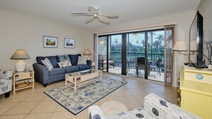 A living room with a sofa, coffee table, and a balcony with outdoor furniture.