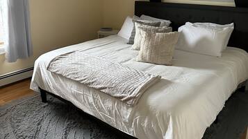 A bedroom with a bed, pillows, a nightstand, and a window with curtains.