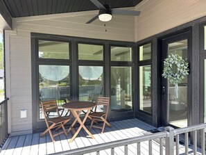 Une terrasse couverte avec une table et des chaises, de grandes fenêtres et un ventilateur de plafond.