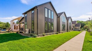 Une maison moderne  à deux étages, dotée d’une grande véranda à l’avant, d’un porche abrité et d’une pelouse bien entretenue.