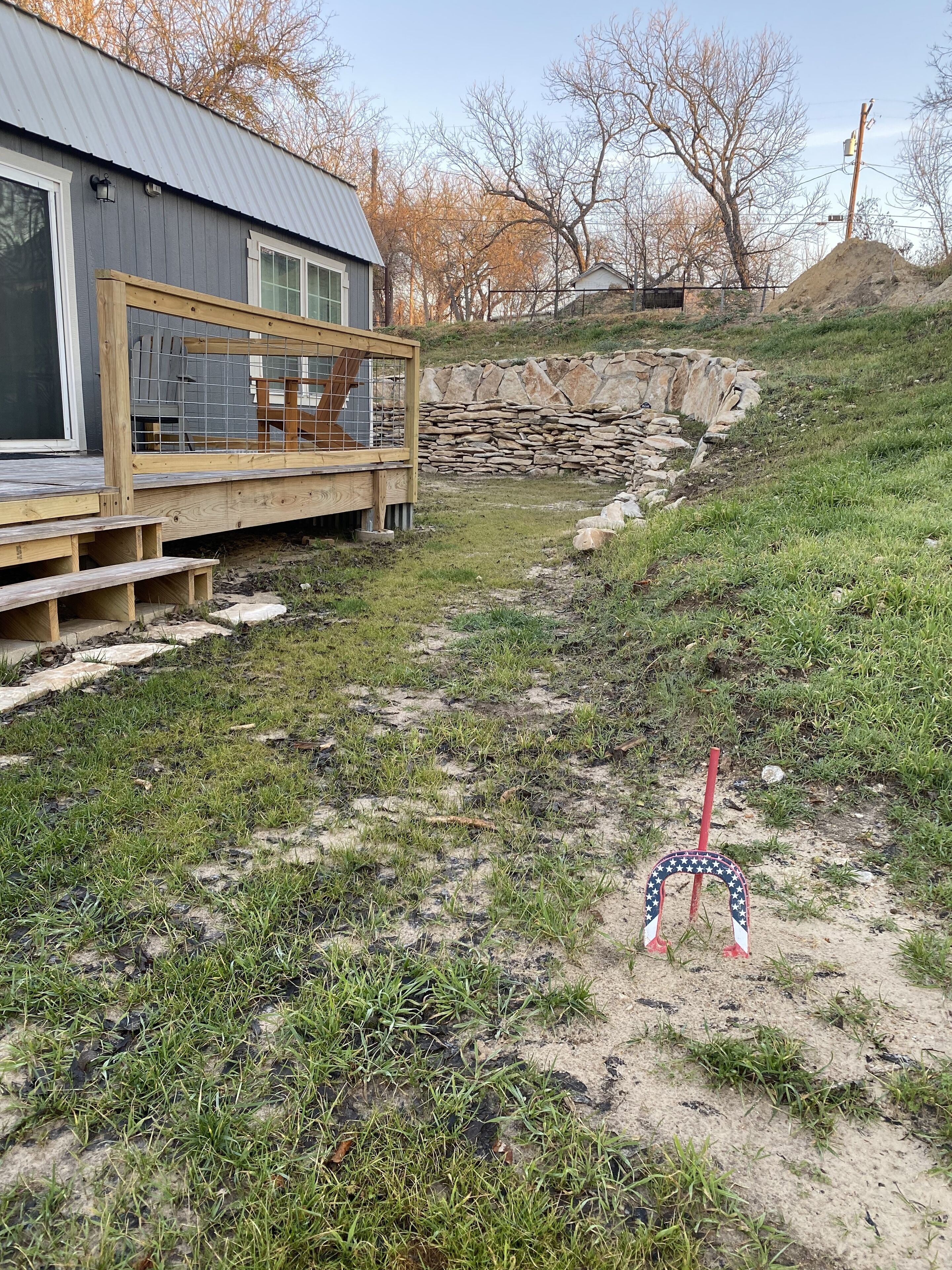 A modern house with a wooden deck and a stone retaining wall.