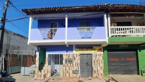 A two-story building with a blue facade, a balcony on the upper floor, and a sign for 'PEDRO CONSTRUCTOR' on the ground floor. - Espaço do Jonga Itacaré-ba (Itacaré)