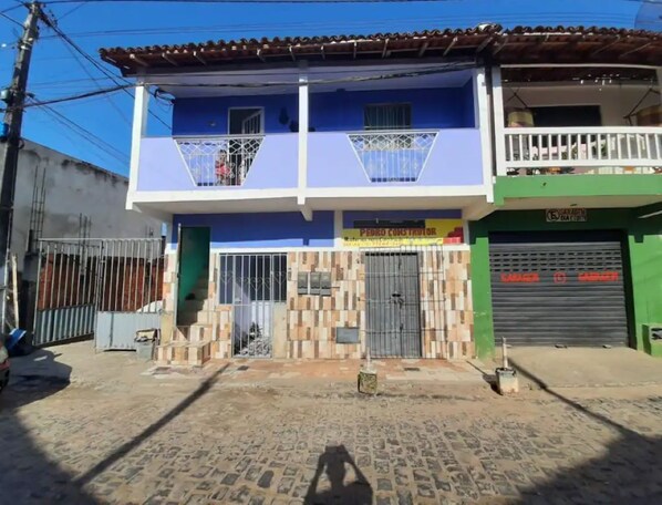 Un bâtiment à deux étages avec une façade bleue, un balcon à l’étage supérieur et une enseigne indiquant « PEDRO CONSTRUCTOR » au rez-de-chaussée.