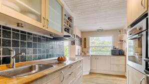 Une cuisine moderne avec des meubles en bois, un évier en acier inoxydable et une fenêtre qui laisse entrer la lumière naturelle.
