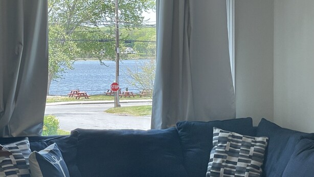Olohuoneessa on sohva, tyynyjä ja sohvapöytä. Ikkunasta näkyy liikennemerkki ja piknikpöytiä.