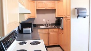A compact kitchen with wooden cabinets, a built-in oven, a sink, and a refrigerator. - Cute & Friendly 1-BR 10 Mins From Nash (Nashville)