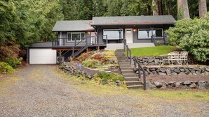 A two-story house with a garage, a covered porch, and a stone staircase leading to the entrance. - Bellingham Waterfront Retreat, Private Dock, Amazing Views (Bellingham)