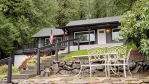 A stone staircase leading to a house with a porch and a white metal bench. - Bellingham Waterfront Retreat, Private Dock, Amazing Views (Bellingham)