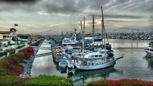 Una marina con barcos amarrados, un puente y un edificio con una bandera.