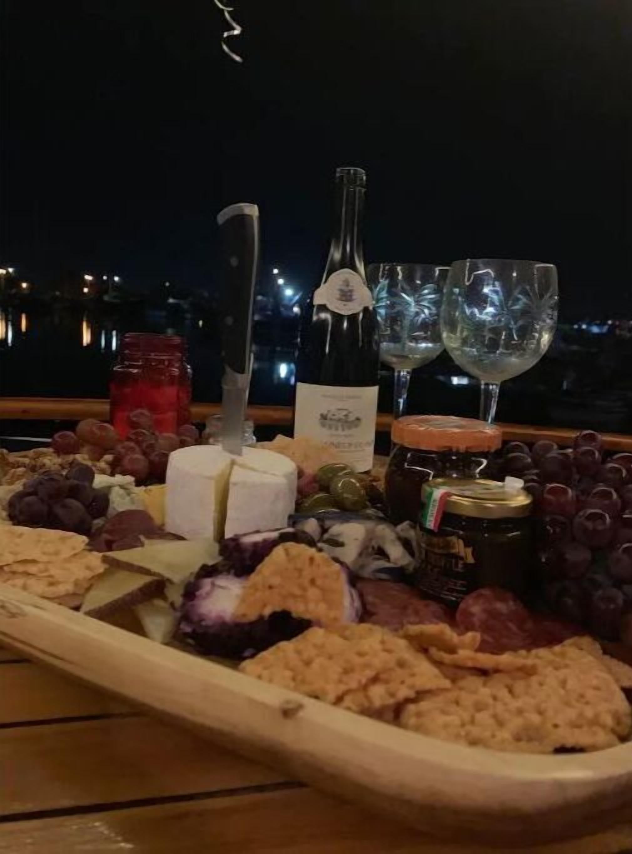 A charcuterie board with cheese, grapes, and crackers on a wooden table.