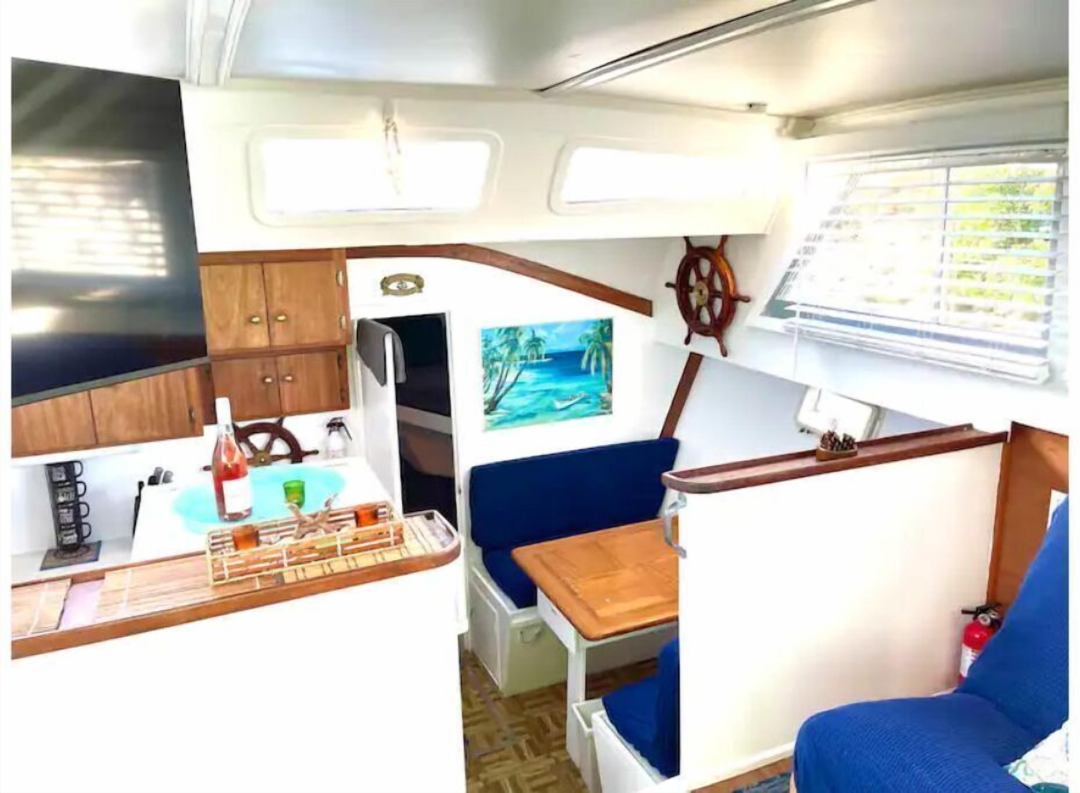 A compact kitchen with wooden cabinets, a sink, and a small dining area with a table and blue seating.