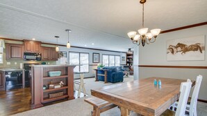 A spacious kitchen with wooden cabinets, a dining table, and a chandelier. - ‘Beach Bay Pony Place’ w/ Ponies: 1 Mi to Water! (Chincoteague)