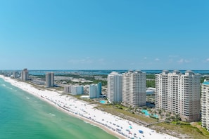 Ein Küstenhotelbereich mit Blick auf den Strand, mehreren Hochhäusern und einem Sandstrand mit Sonnenschirmen.