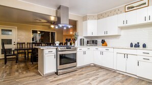 A modern kitchen with white cabinets, a stainless steel stove, and a microwave. - Ultimate Relaxation Retreat w/ Game Room & Hot Tub (Ahwahnee)