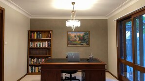 Un bureau à domicile avec un bureau, une bibliothèque et un tableau accroché au mur.