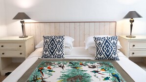 Un lit avec une couvre-lit à motifs, deux oreillers et deux tables de chevet avec des lampes.