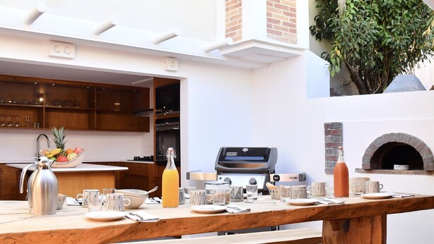 Une cuisine extérieure équipée d’un barbecue, d’un four et d’une table à manger.