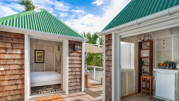 Een knus vakantiehuis met een houten gevel, een slaapkamer met een bed, een kitchenette en een terras.