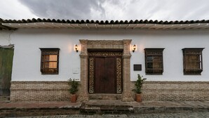 Un bâtiment traditionnel avec un toit en tuiles, une porte en bois ornée de sculptures et deux plantes en pot de chaque côté.