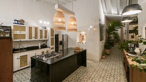 Une cuisine moderne dotée d’un îlot central, de luminaires suspendus et de plantes en pot.