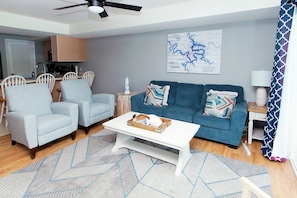 A modern living room with a sofa, chairs, a coffee table, and a map on the wall. - Clean 2BD 2BA Condo w Slip - 5 Minutes to Bagnell Dam!  Plus Pool & Swim Dock!  (Lake Ozark)
