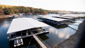 A marina with multiple docks and boats, surrounded by a forested area.