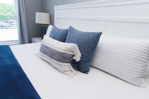 A neatly made bed with a white headboard, a blue throw blanket, and two blue pillows. - Clean 2BD 2BA Condo w Slip - 5 Minutes to Bagnell Dam!  Plus Pool & Swim Dock!  (Lake Ozark)
