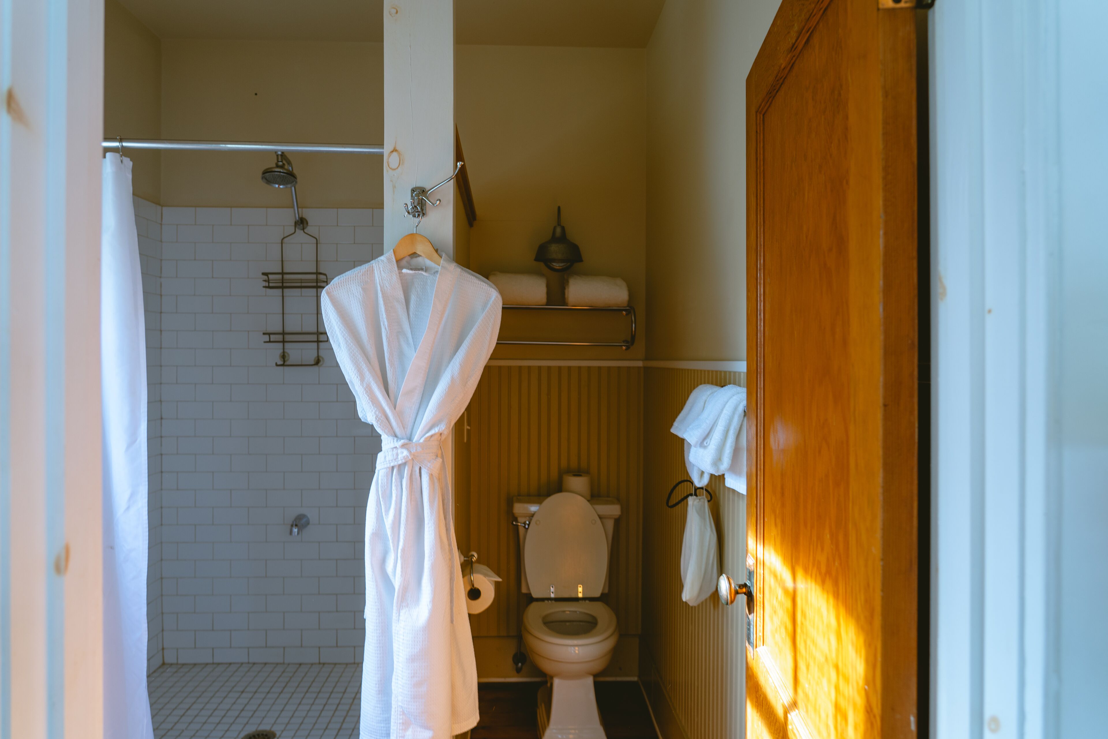 A bathroom with a shower, toilet, and towel rack.